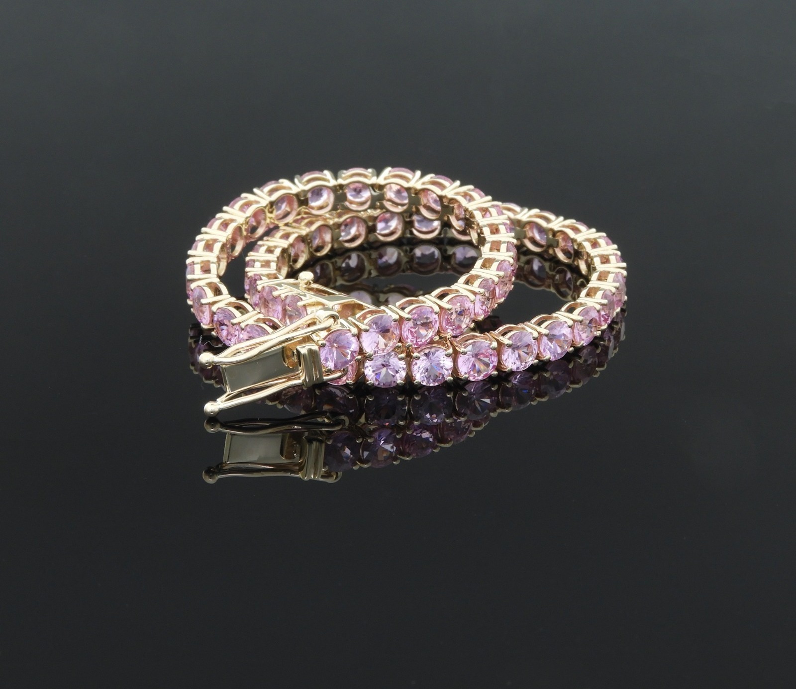 Round pink stones in a delicate gold tennis-bracelet setting.