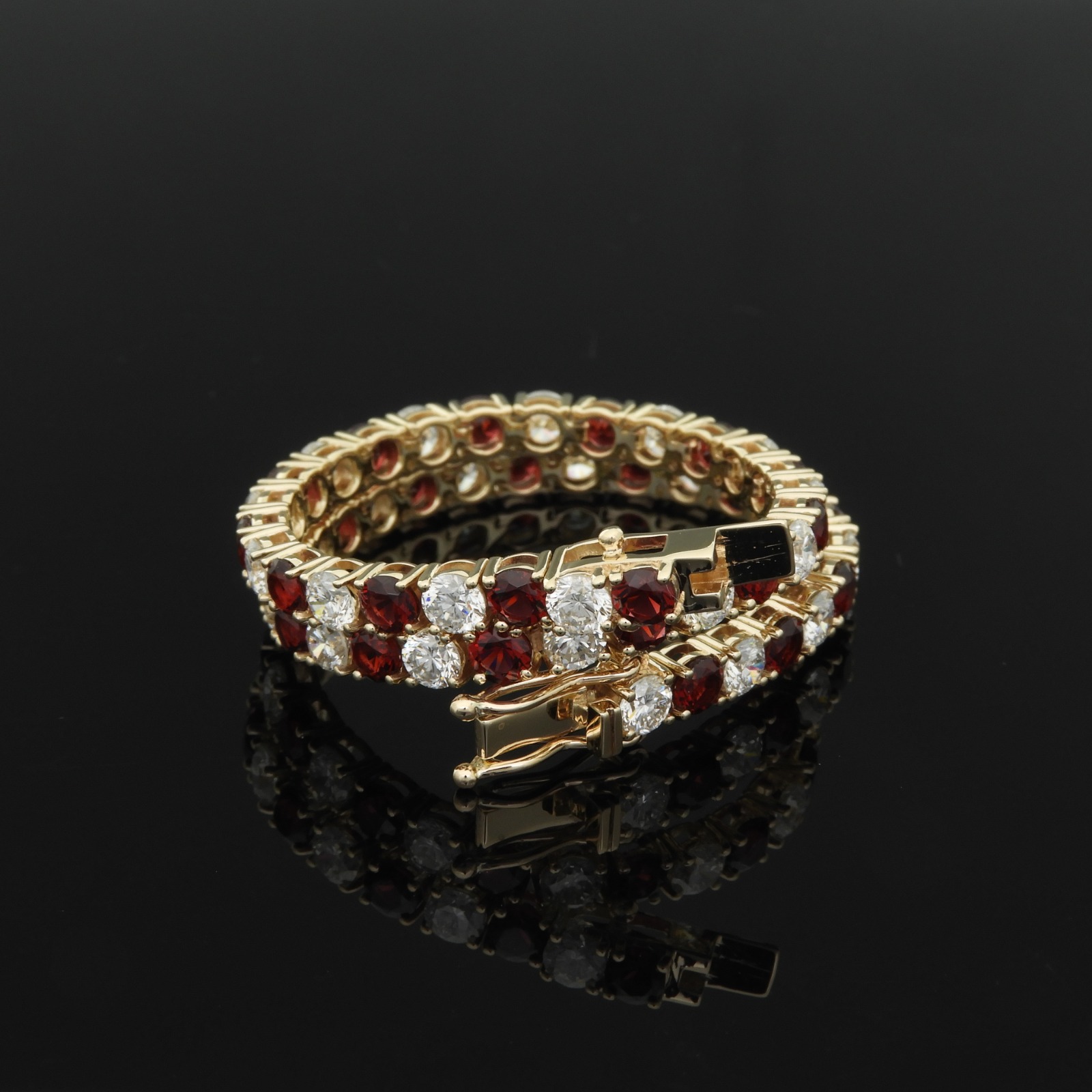 Alternating round red and clear stones in a wrap-style tennis bracelet, yellow gold.